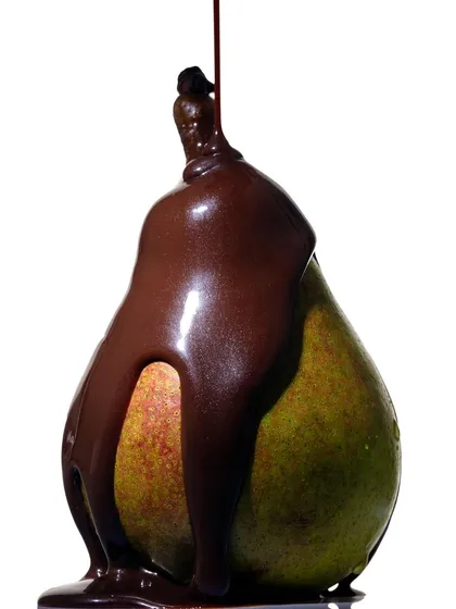 A simple yet decadent concept of liquid chocolate being poured over a fresh pear. This shot from my personal series focuses on the thick, glossy texture of the chocolate as it envelops the fruit.