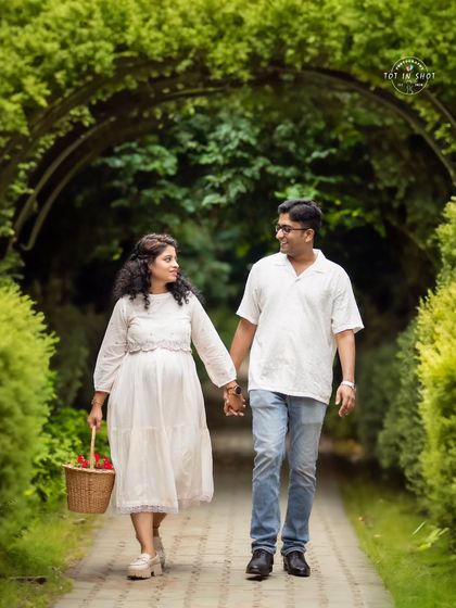 A happy couple takes a stroll through a lush green archway, a perfect setting for an outdoor traditional shoot.