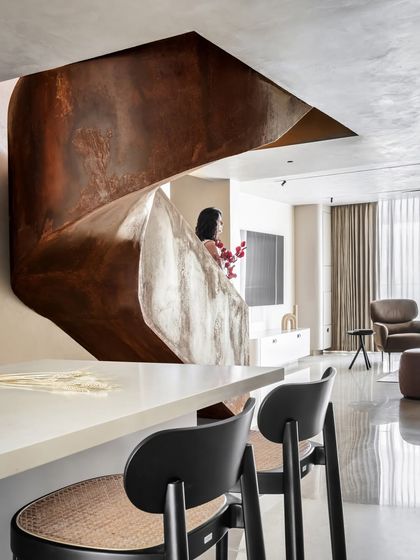 The sculptural Corten steel staircase is the heart of the Terra Gardens penthouse. Its raw, rustic finish and sweeping curves stand in beautiful contrast to the polished floors and minimalist decor, blending art with functionality.