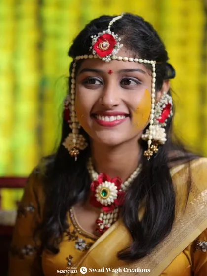 A beautiful portrait of a happy Haldi bride. The red flower in her maang tika and necklace adds a pop of color to the delicate white floral set.