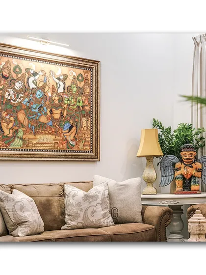 This living room corner is rich with character, featuring a large, intricate traditional painting above a comfortable leather sofa. The quirky winged figurine on the side table adds a playful and unexpected element to the decor.