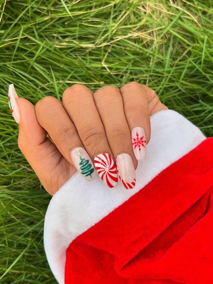 This angle shows the Christmas nail art against a Santa hat, highlighting the festive red and white color scheme.
