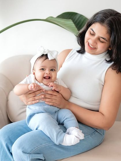 A mother and baby sitting on the couch together.
