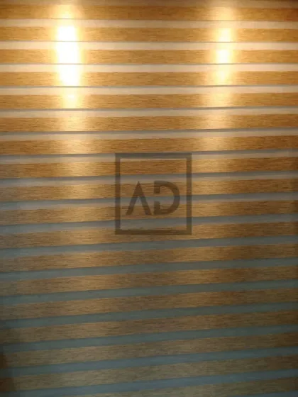 Here, the wooden zebra blinds are fully closed, providing privacy and a warm, textured wall effect. The backlighting highlights the clean, horizontal lines that are characteristic of this popular blind style.