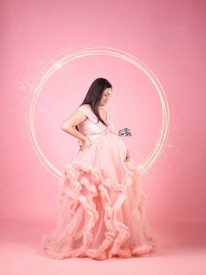 A touch of sparkle for a magical moment. This shot highlights the beautiful silhouette of the pink ruffled gown, perfect for capturing that pregnancy glow in the studio.