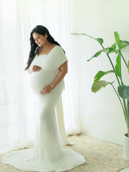 Capturing the essence of motherhood in a moment of grace and anticipation. This full-length portrait in a fitted white gown is both elegant and serene.