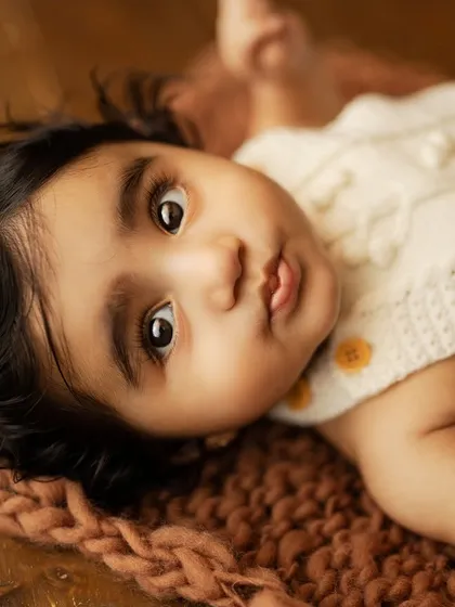 Those big, expressive eyes. This close-up shot of a baby lying on a textured mat captures the innocence and wonder of early childhood.