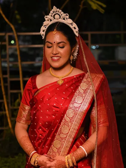 Piyashi in her full Bengali bridal attire. The red Banarasi saree, mukut, and minimal makeup come together for a look of pure grace.