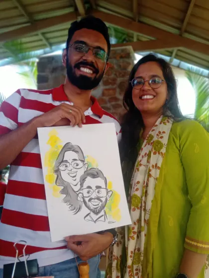 A couple holding their caricature, drawn live at an event. I use a touch of color to make the portraits pop.
