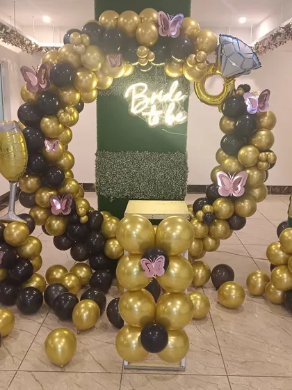 For a bold and glamorous bridal shower, I used a black and gold color scheme. This balloon ring backdrop is accented with a "Bride to be" neon sign and large foil balloons of a diamond ring and a champagne bottle for a fun, celebratory theme.