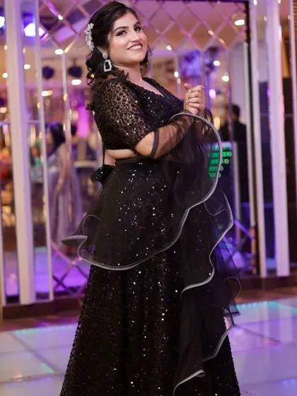 A full view of the sparkling black lehenga. The makeup is kept glamorous with a focus on the eyes.