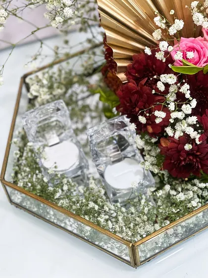 A modern and chic floral ring platter. This hexagonal mirrored tray is filled with baby's breath and adorned with a dramatic arrangement of red and gold florals.