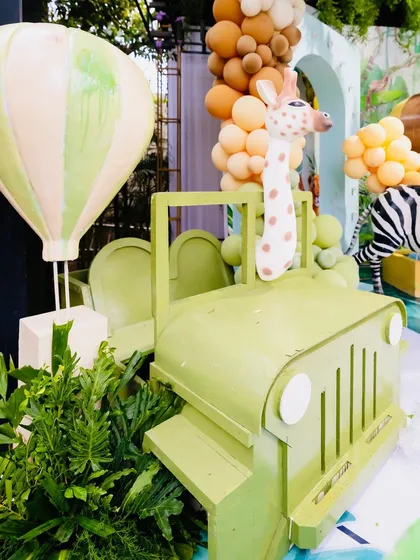 A fun safari jeep prop with a giraffe peeking out, part of Eshaan's jungle adventure theme. The green jeep and hot air balloon add to the exploration vibe.