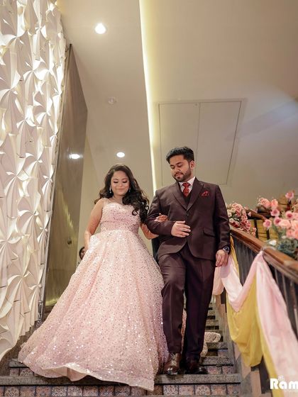 The grand entrance of the couple at their engagement party. The bride's princess gown and the elegant staircase create a dramatic and beautiful start to the celebration.