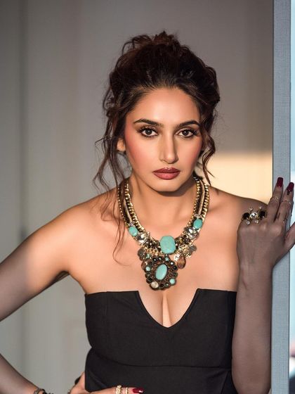 A glamorous portrait highlighting a chunky turquoise necklace. The lighting is carefully placed to create a catchlight in the eyes and define the model's features.