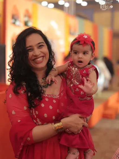 A happy photo of me and Gauri in matching red outfits for a "Mayra" ceremony. This shows how we dress up for family functions, creating opportunities for ethnic wear and kids' fashion brands to be featured.