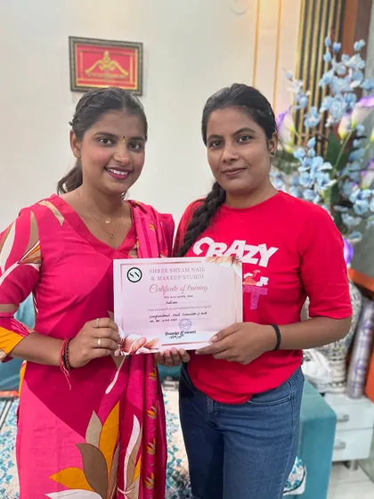 A happy student holding her certificate of training after completing the professional nail art course.