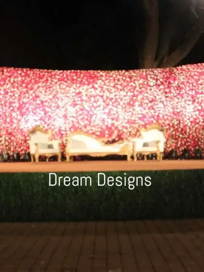 A truly grand statement stage featuring a massive wall of pink and white flowers. The sheer scale of the floral backdrop creates an impactful and luxurious setting for a large reception.