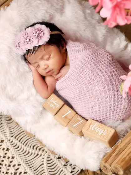 This 17-day-old newborn is beautifully wrapped in pink and resting in a basket. The flowers add a soft, delicate touch to this classic newborn portrait.