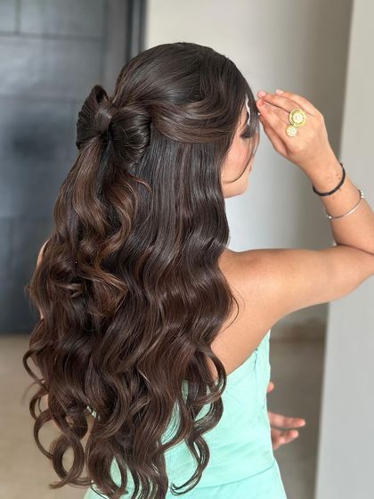 A flowing, effortless bow hairstyle made from the hair itself. This half-up style with soft curls is incredibly romantic and chic.