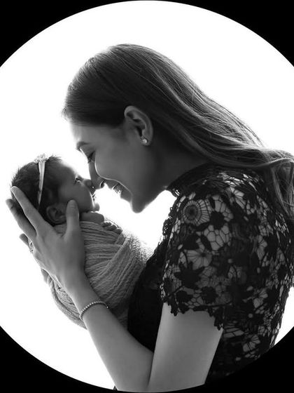 A timeless black and white silhouette of a mother and her newborn twin. The circular frame focuses all attention on their nose-to-nose connection.