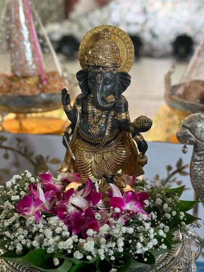 A stunning black and gold Ganesha idol, beautifully decorated with orchids and baby's breath.