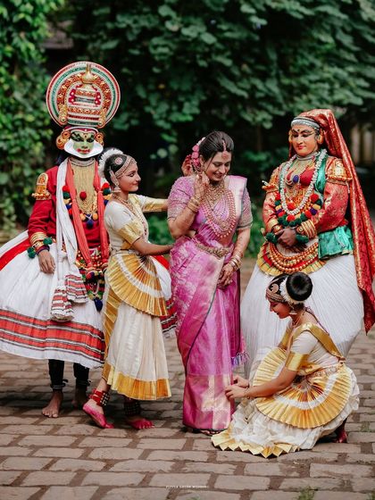 The bride poses with Kathakali and Mohiniyattam dancers, a beautiful fusion of wedding celebrations and Kerala's rich cultural arts.