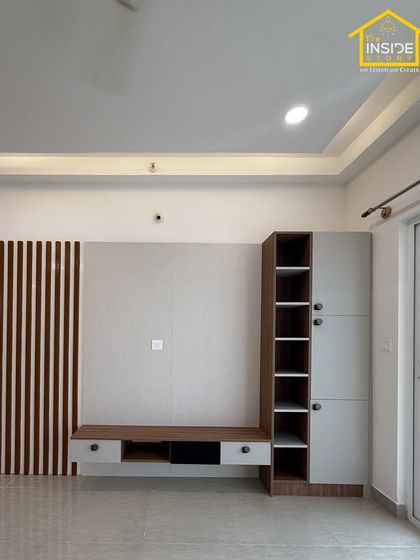 This TV unit design combines a light-colored back panel with a dark wood floating console and a tall storage cabinet, offering a mix of open and closed storage for a balanced look.