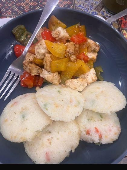 A plate of vegetable idli with sautéed paneer and bell peppers. A creative and nutritious meal that is part of a client's successful transformation.