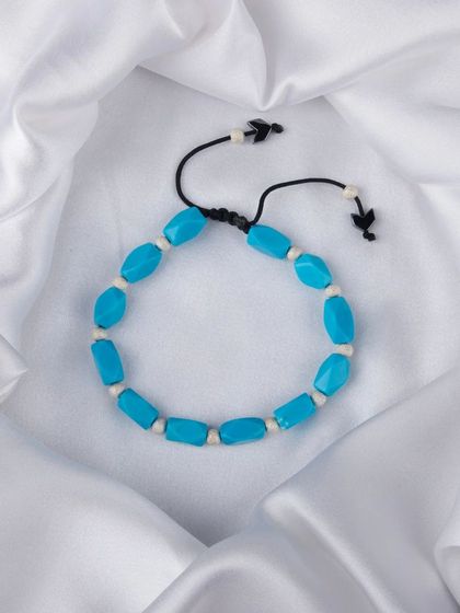 A bracelet made of rectangular turquoise-colored beads on a black cord.
