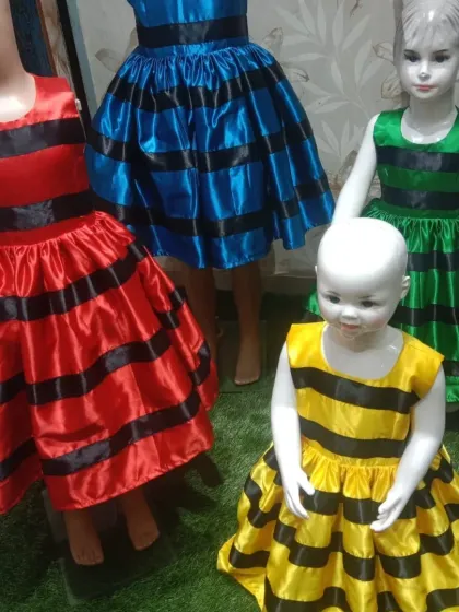A vibrant collection of satin balloon frocks in red, blue, green, and yellow, displayed on mannequins to show some of the styles available for bulk orders.