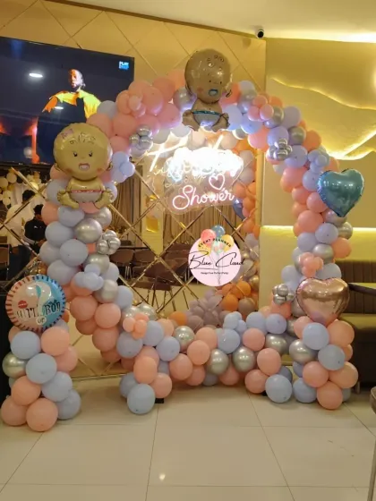 A baby shower balloon arch in pastel pink, blue, and silver, perfect for a restaurant or small venue.