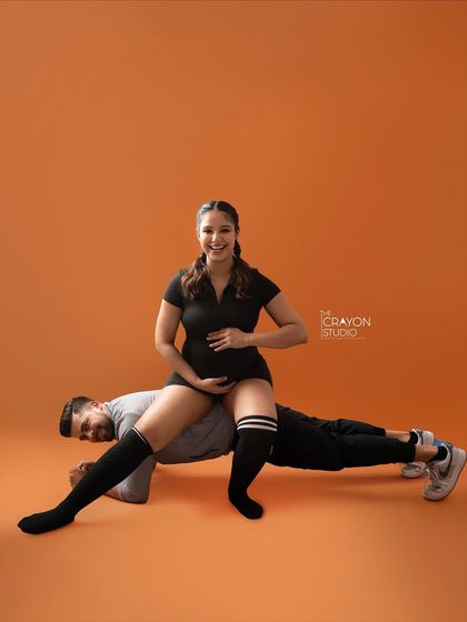 A playful and strong pose, with her sitting on his back as he holds a plank. This couple's fun personality shines through in their creative maternity shoot.