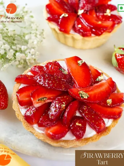 A beautiful Strawberry Tart, featuring a buttery crust, a creamy filling, and a topping of fresh, glossy strawberries with edible gold flakes.
