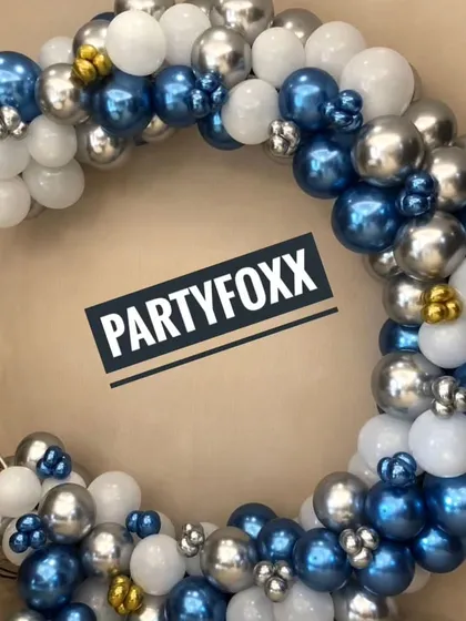 A stylish circular balloon arrangement in metallic blue, silver, and white, perfect for a modern and sophisticated adult party or corporate event.