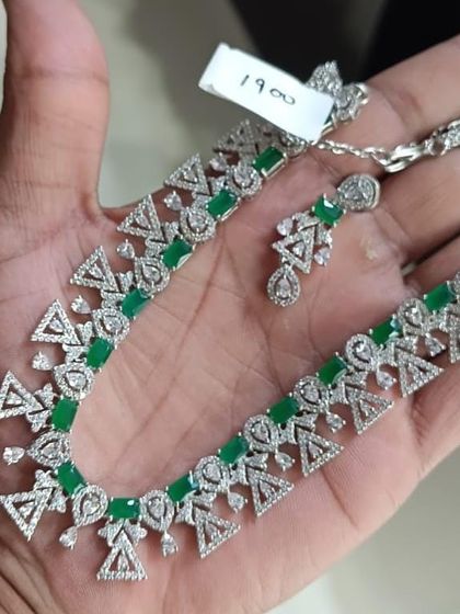 A modern American Diamond necklace with a unique geometric design, featuring triangles and green rectangular stones.