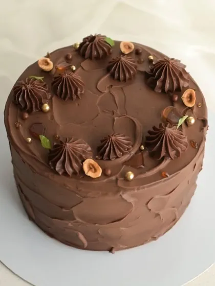 My Hazelnut Praline cake is a crowd favorite. It's a rich chocolate cake decorated with piped ganache, toasted hazelnuts, and crunchy praline pieces.