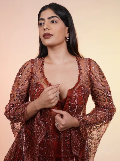 A close-up of the rust-colored Indo-Western outfit, focusing on the embellished corset top and sheer jacket.
