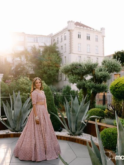 The bride stands in a beautifully landscaped garden, the golden hour sun casting a warm glow on her. This portrait captures her elegance and the beauty of the Turkish venue.