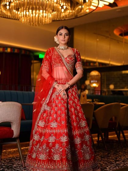 Another angle of this regal bridal look. The lighting in the venue highlights the rich red of her outfit and the flawless finish of her makeup.