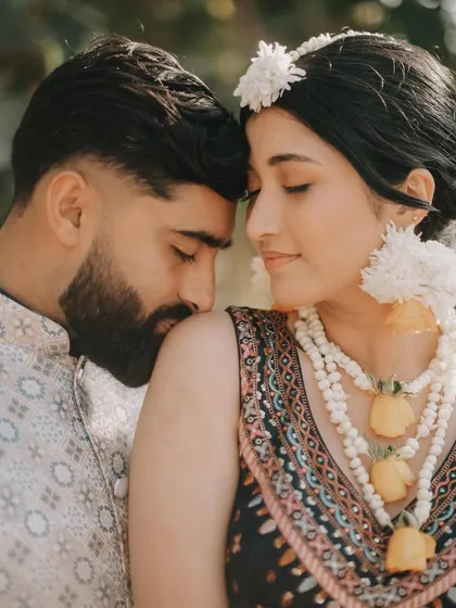An intimate close-up of Rahul and Anjali. The floral jewelry and their gentle embrace create a soft, romantic, and traditional feel.