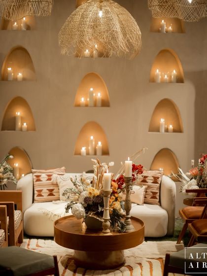An intimate seating area from the 'Muted Melodies' sangeet, featuring arched candle niches and rattan pendants. The design used a symphony of muted tones and textures to create a harmonious space.