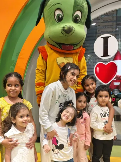 A sweet group photo of young children smiling and hugging while posing with the Tinga Dojo mascot.