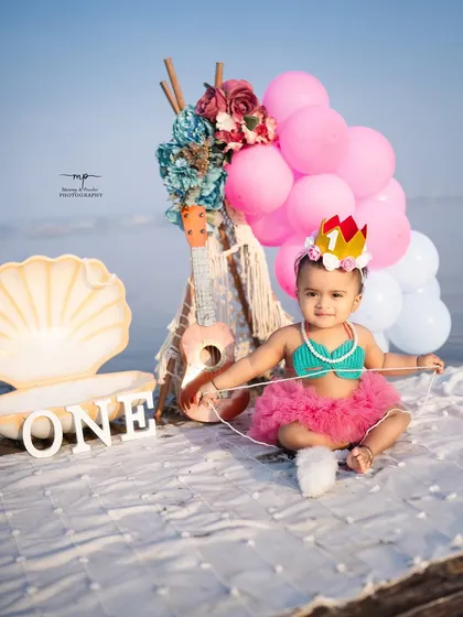 A full view of the adorable mermaid-themed first birthday setup on the beach. The vibrant pinks and blues stand out against the natural backdrop, creating a picture-perfect scene.