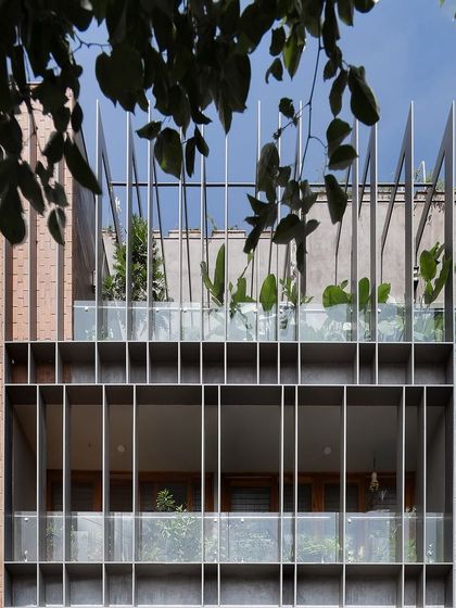 The facade is a mix of open terraces and shaded balconies. The vertical metal fins provide sun protection and a sense of enclosure for the outdoor spaces, allowing residents to enjoy the views in comfort.