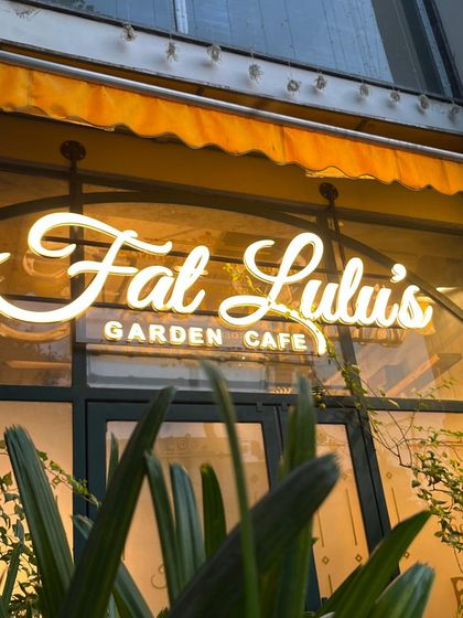 The glowing sign of my Fat Lulu's Garden Cafe, a welcoming sight for all food lovers.