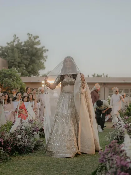 The bride's playful peek-a-boo moment during her entrance. Ishita's joyful expression as she lifts her veil to see her groom is a perfect blend of tradition and modern fun.