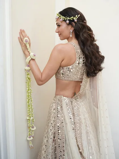 This view from the back showcases the bride's stunning Arpita Mehta lehenga and half-up hairstyle. My goal was to create a 360-degree look, ensuring her skin looked just as radiant and flawless from the back.