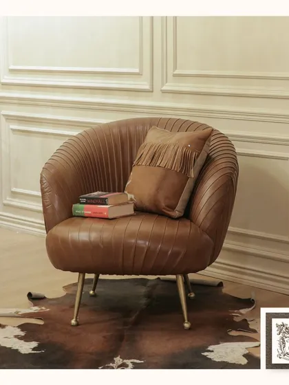 This pleated leather club chair is a study in texture and form. Placed on a genuine hide rug, its curved silhouette and delicate metal legs offer a modern take on classic comfort, making it a perfect accent for any sophisticated corner.