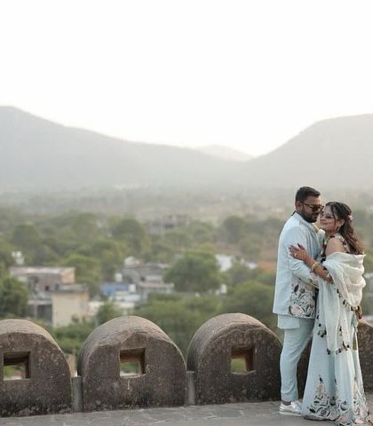 A serene portrait overlooking the Aravalli hills from a historic fort near Jaipur. This image captures a quiet moment of togetherness, with the vast, hazy landscape providing a stunning backdrop.